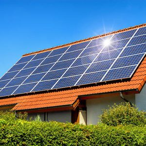 Solar panel on a red roof reflecting the sun and the cloudless blue sky